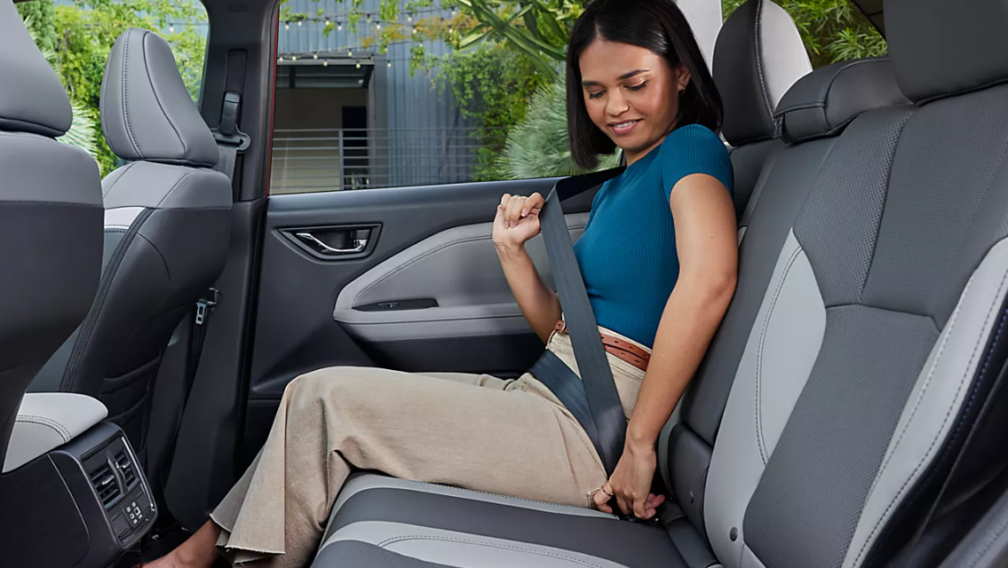 A woman buckles her seat belt in the backseat of a 2024 Subaru Forester
