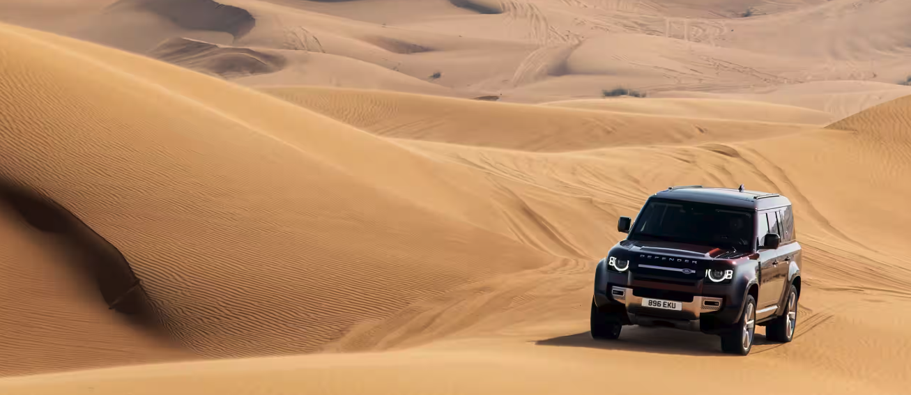 Front view of the 2024 Defender driving through sand