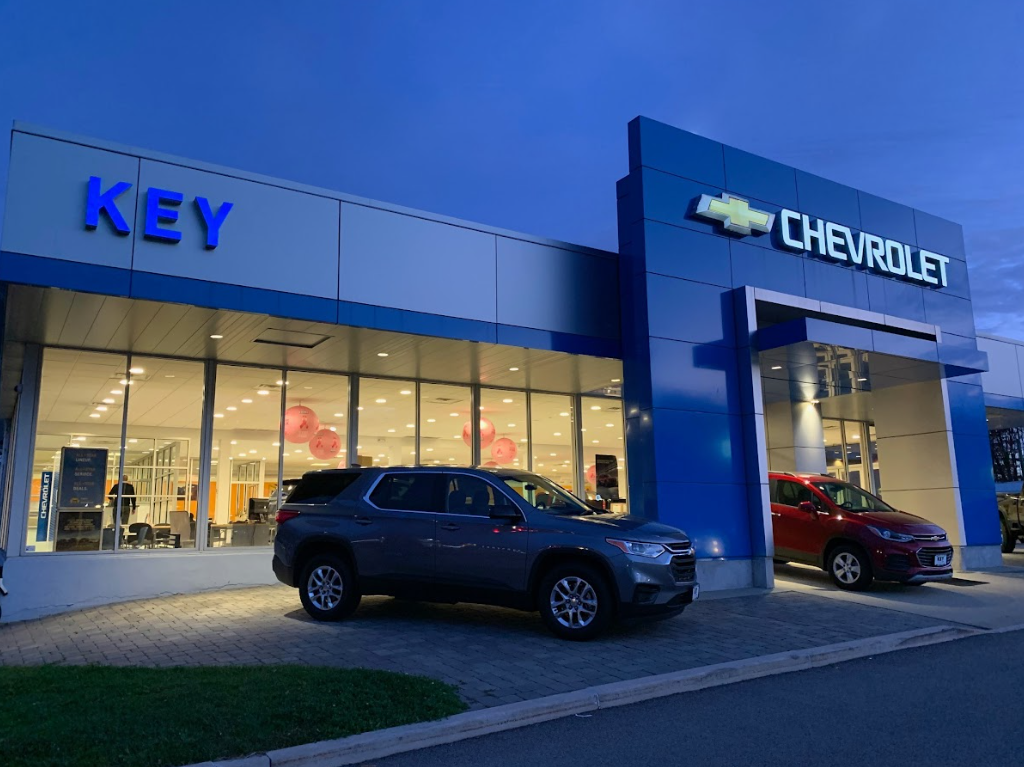 The front of Key Chevrolet's showroom at dusk. Two Chevy vehicles are parked on the apron in front