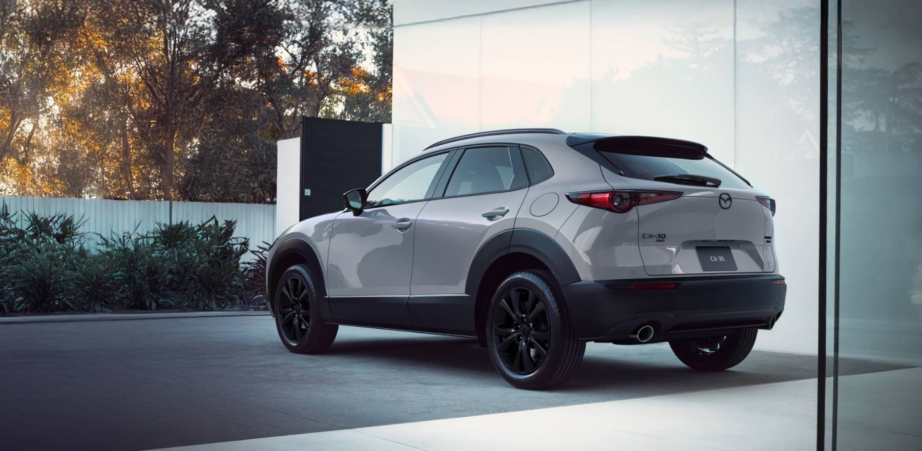 A gray Mazda CX-30 parked outside a nice, white house.