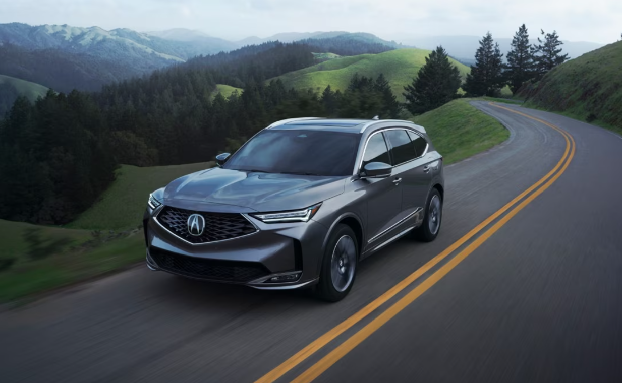 A man leans against a gray Acura Integra. A black Acura Integra is alongside the gray