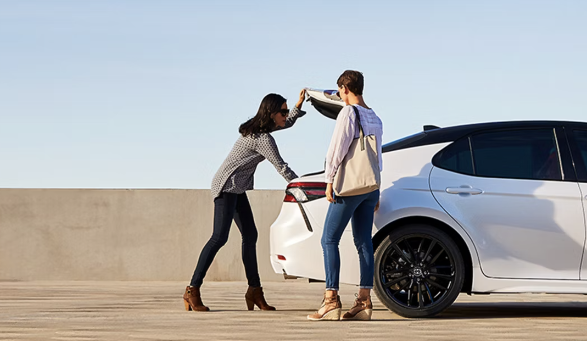 Two women behind a 2024 Toyota Camry