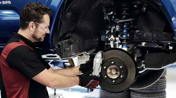 Man in safety glasses repairing a brake on a vehicle