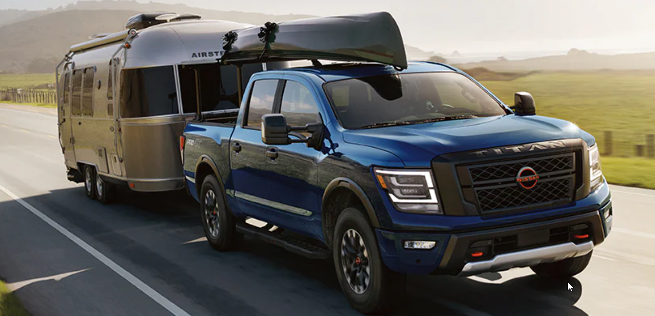 2024 Nissan Titan Crew Cab 4x4 with a canoe on the roof towing a large trailer
