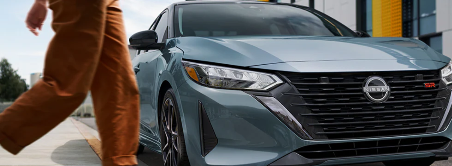 A person wearing orange pants approaches a green 2024 Nissan Sentra SR