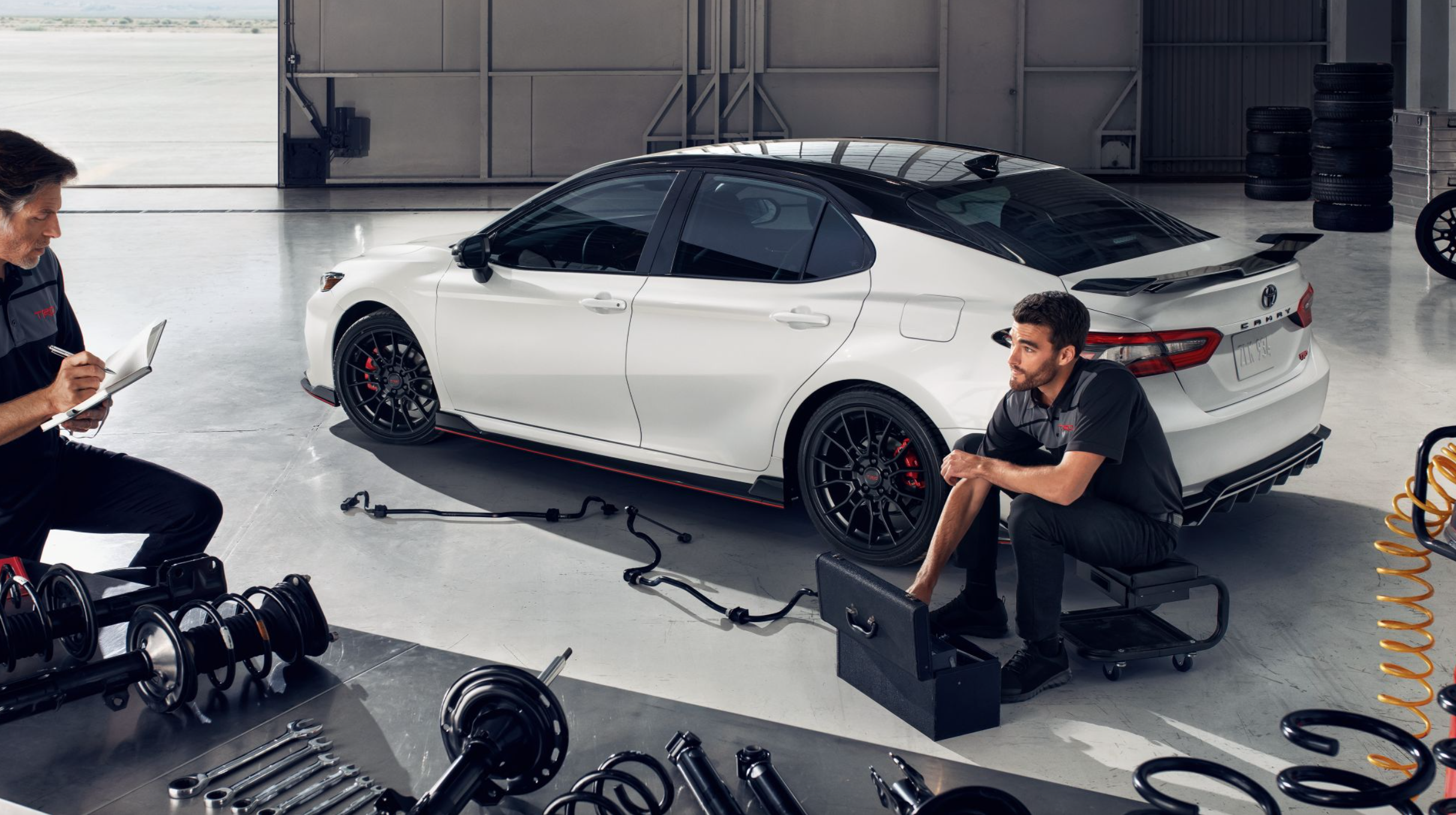 Two Toyota service technicians in front of the 2024 Toyota Camry