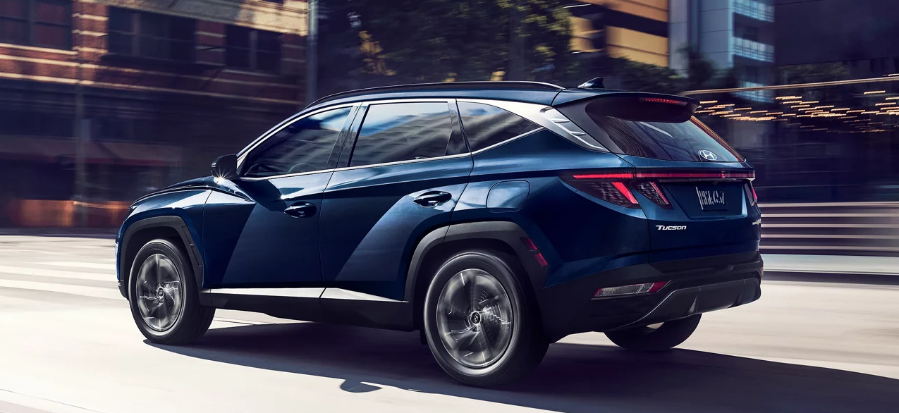 A 2024 Hyundai TUCSON drives quickly through an urban environment