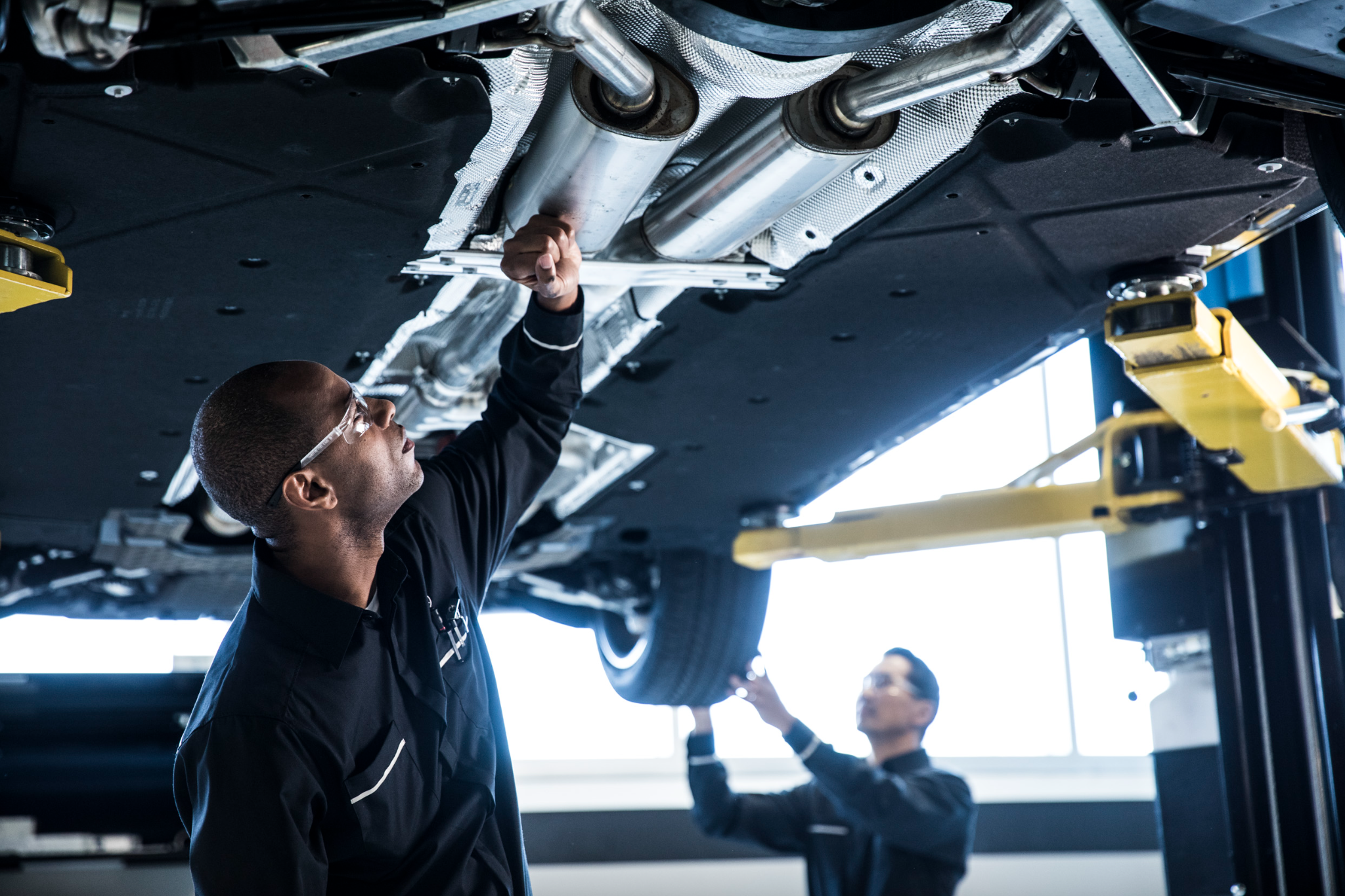 Two Mercedes-Benz technicians working underneath a vehicleTwo Mercedes-Benz technicians working underneath a vehicle