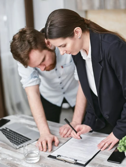 A man and woman look at a paper with small text on a clipboard