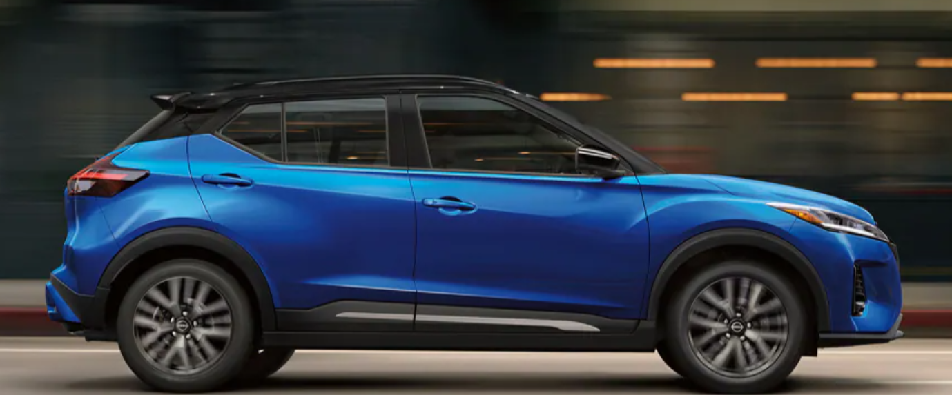 A blue and black 2024 Nissan Kicks driving quickly on a city street