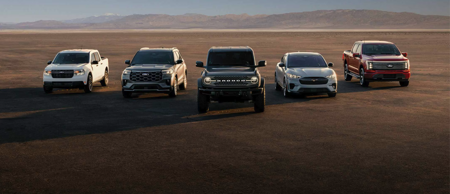 Five Ford vehicles lined up in a row with mountains in the background