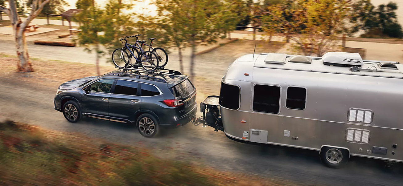 A gray 2024 Subaru Ascent Touring with two bicycles on the roof pulling a silver Airstream trailer